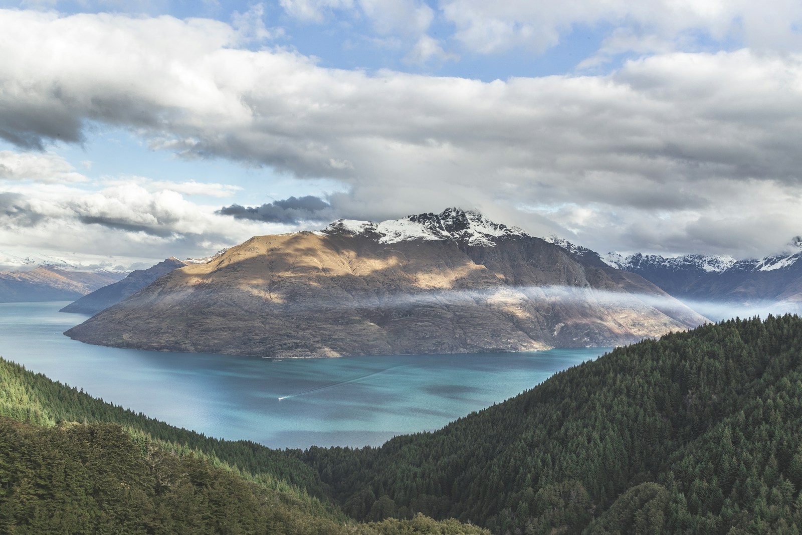 Mountain fjord with snow-capped peaks reflected in still water, winter morning